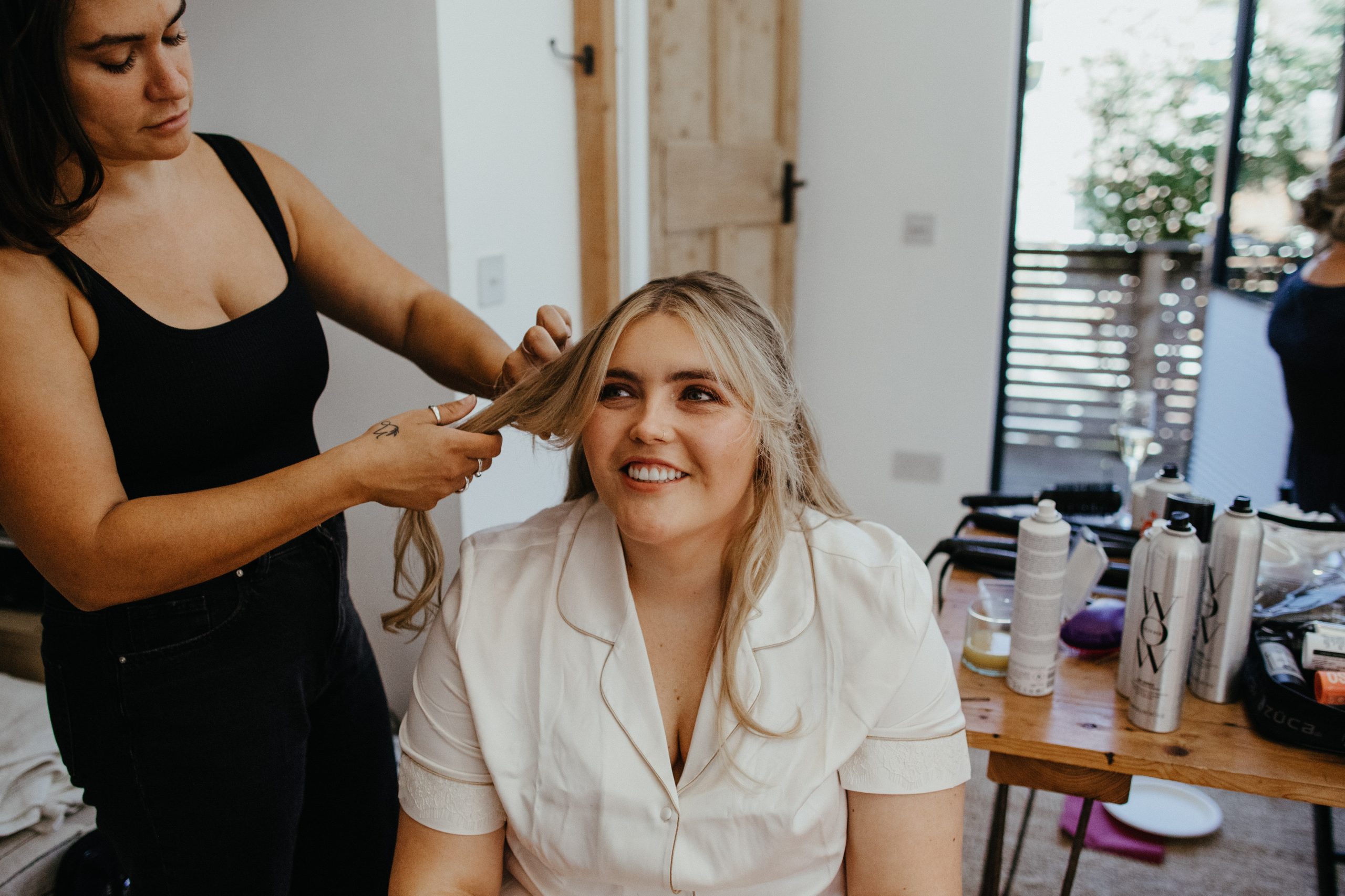 Amelia Carmela Bristol and Wiltshire bridal hair stylist curling blonde hair at a wedding 